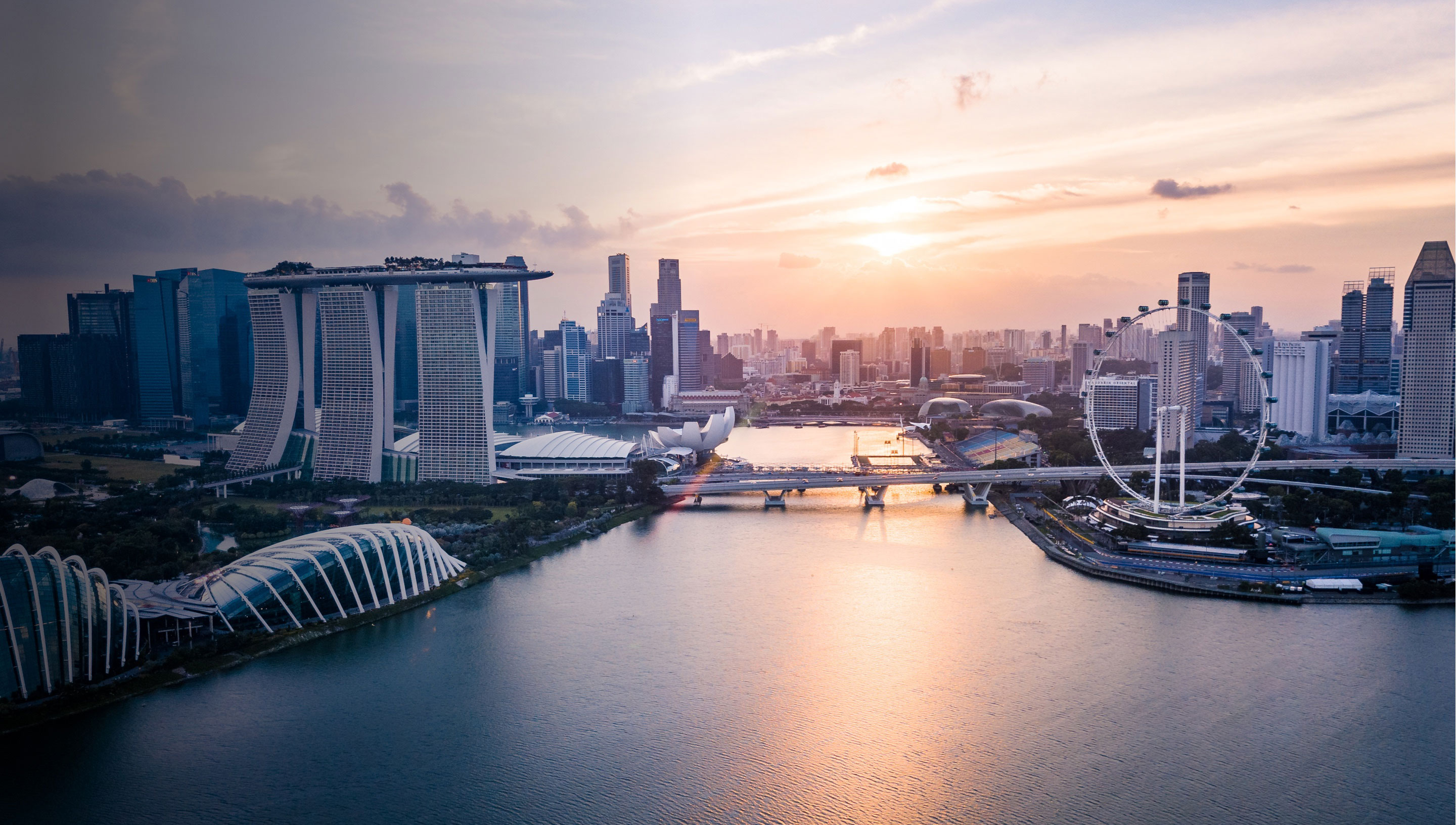 A cityscape of the Singapore Marina at dawn, showing the Singapore Flyer