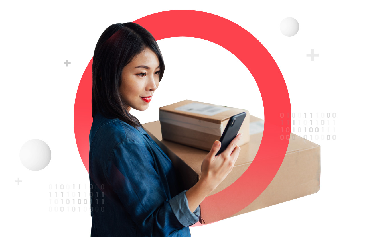 Woman holding boxes with one arm, looking at phone in her other hand