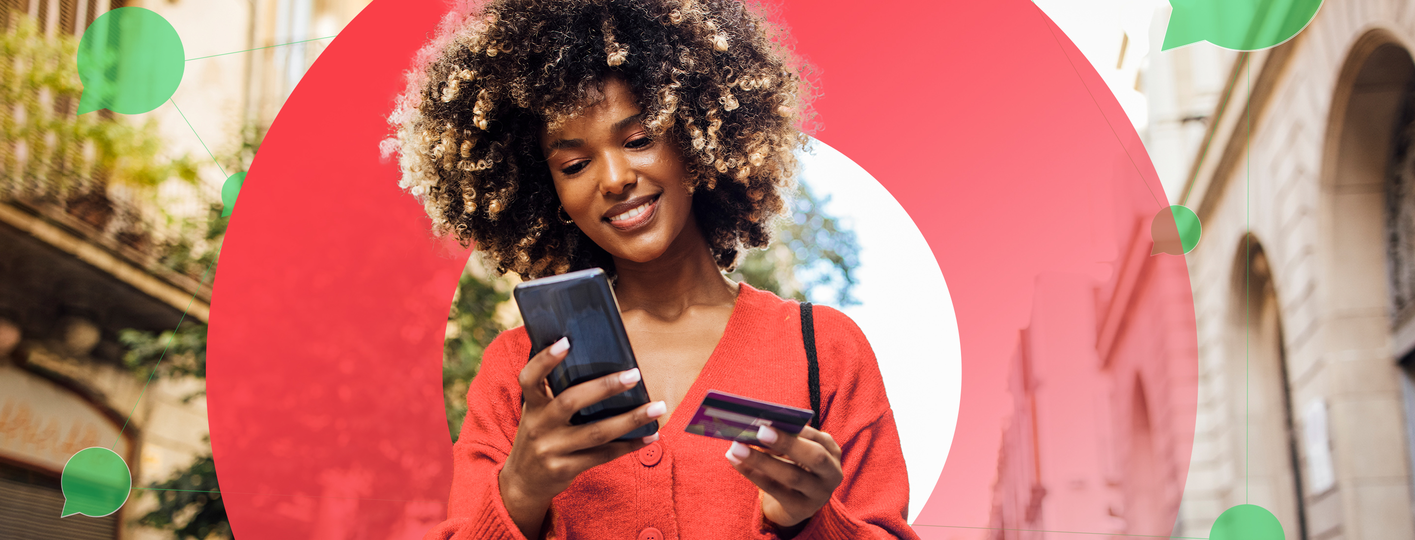 A smiling person holding a credit card and a phone while shopping online.