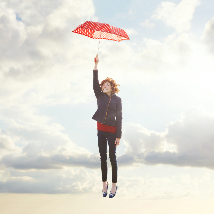 person holding umbrella as it rises into the sky