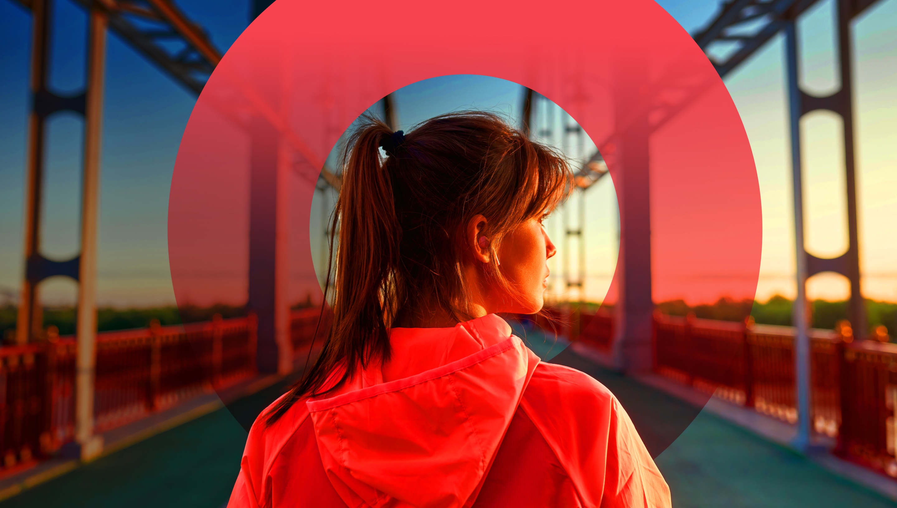 Woman standing on bridge looking out to the right against the horizon.