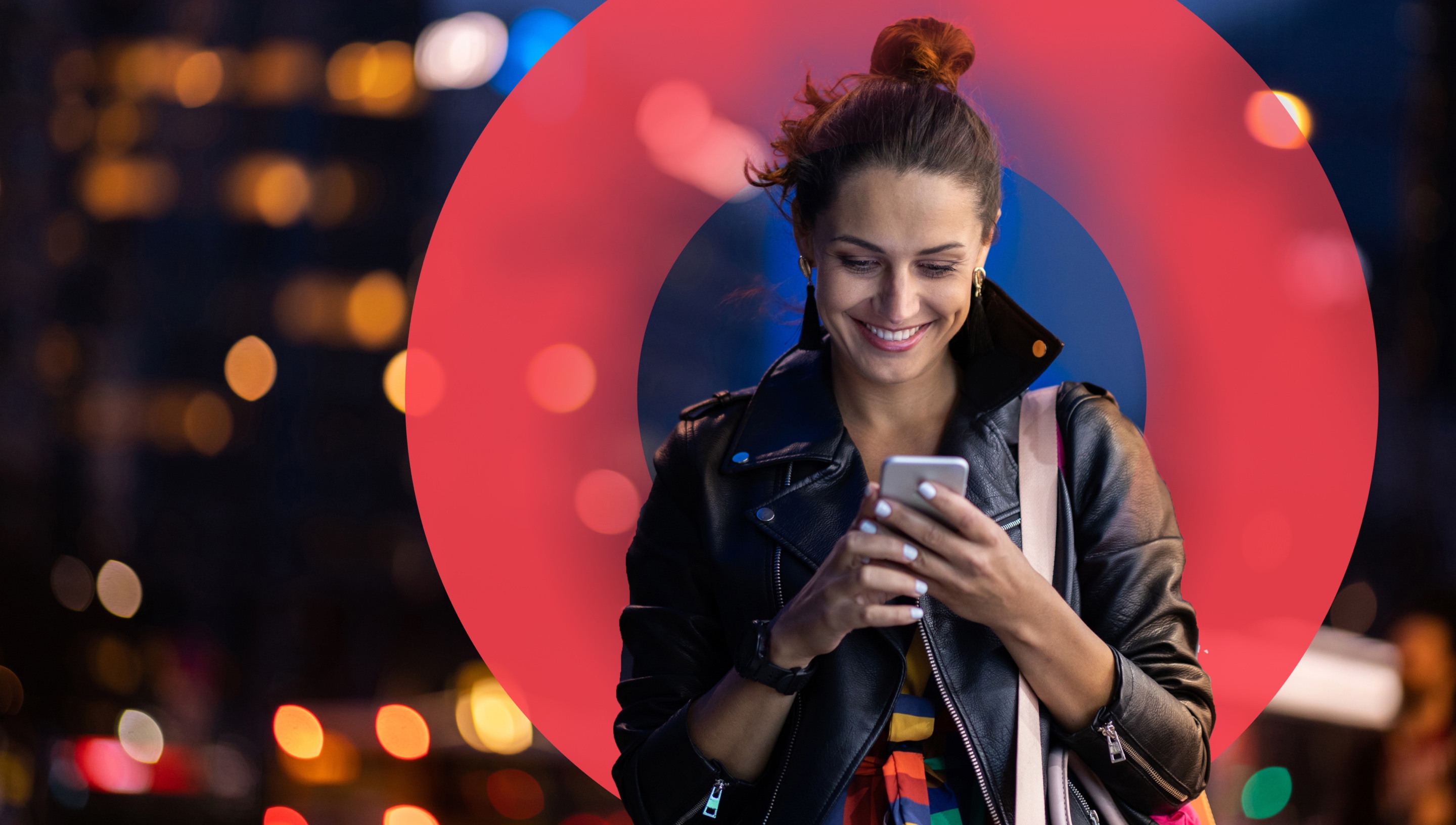 Woman holding cell phone in two hands; looking at cell phone and smiling