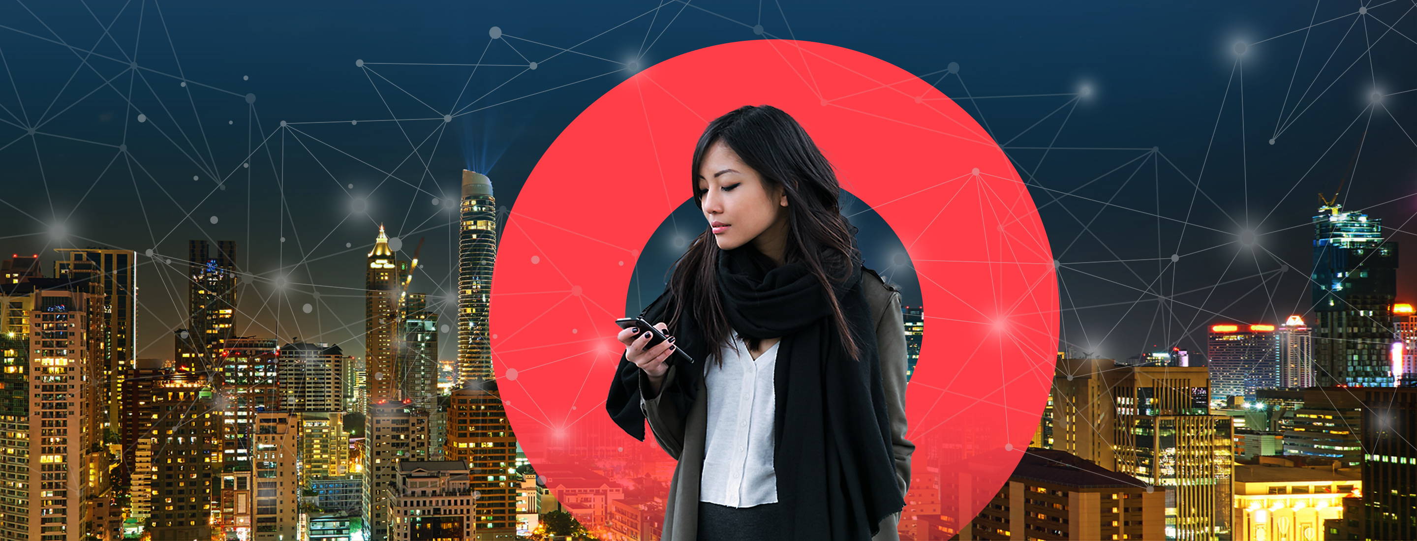 Businesswoman looks at her phone on a rooftop overlooking night cityscape.