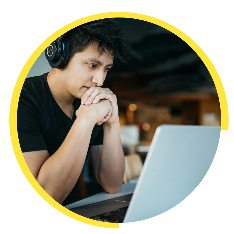 A young person wearing headphones, looking at laptop