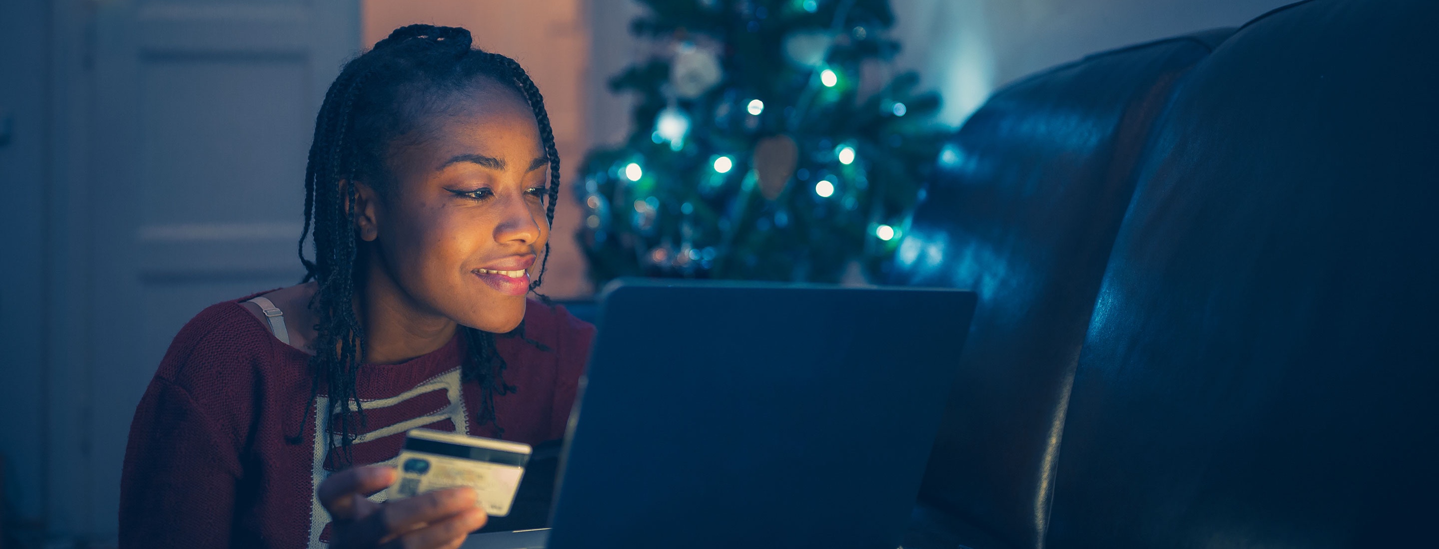 Woman using a credit card to but holiday gift online at home