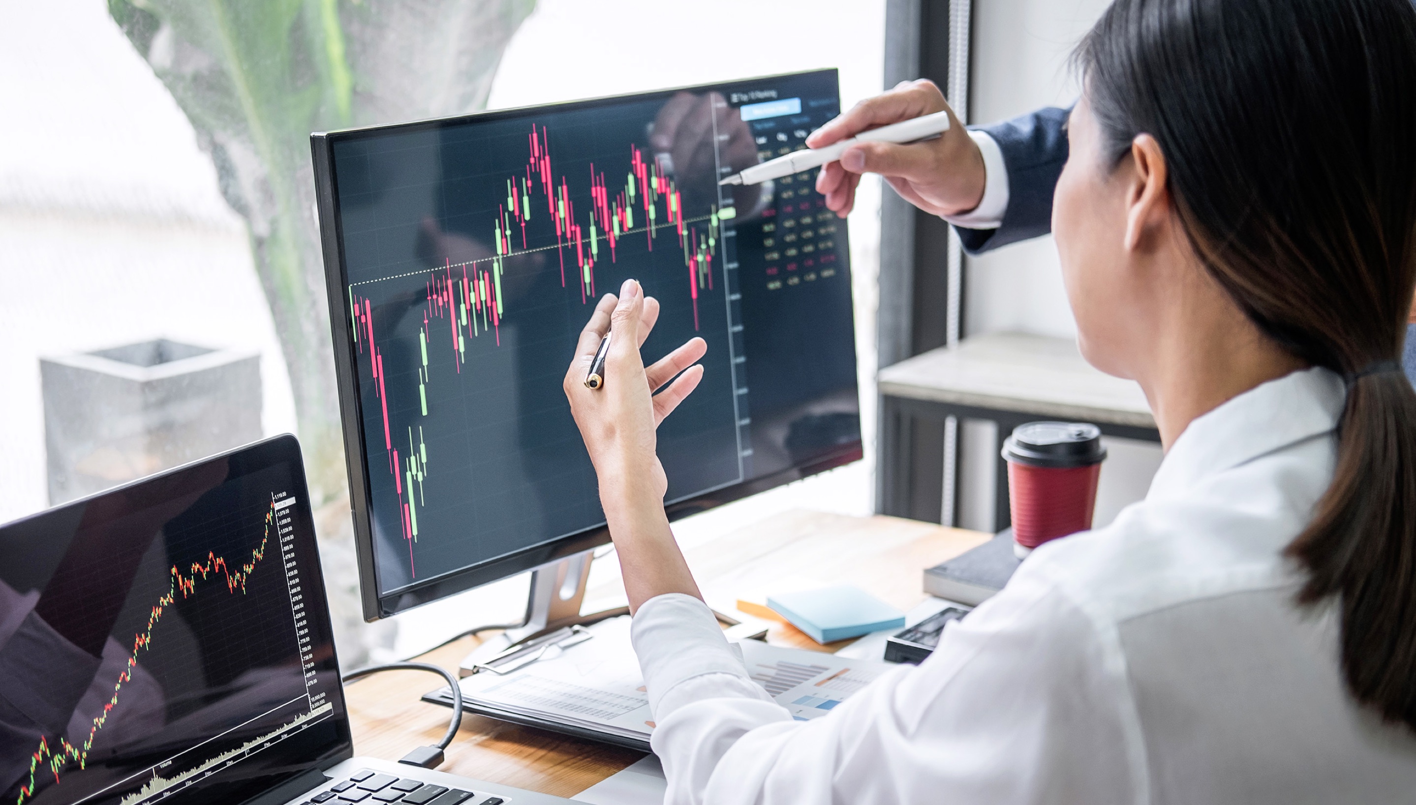 Woman working on a computer that has a stock trading chart