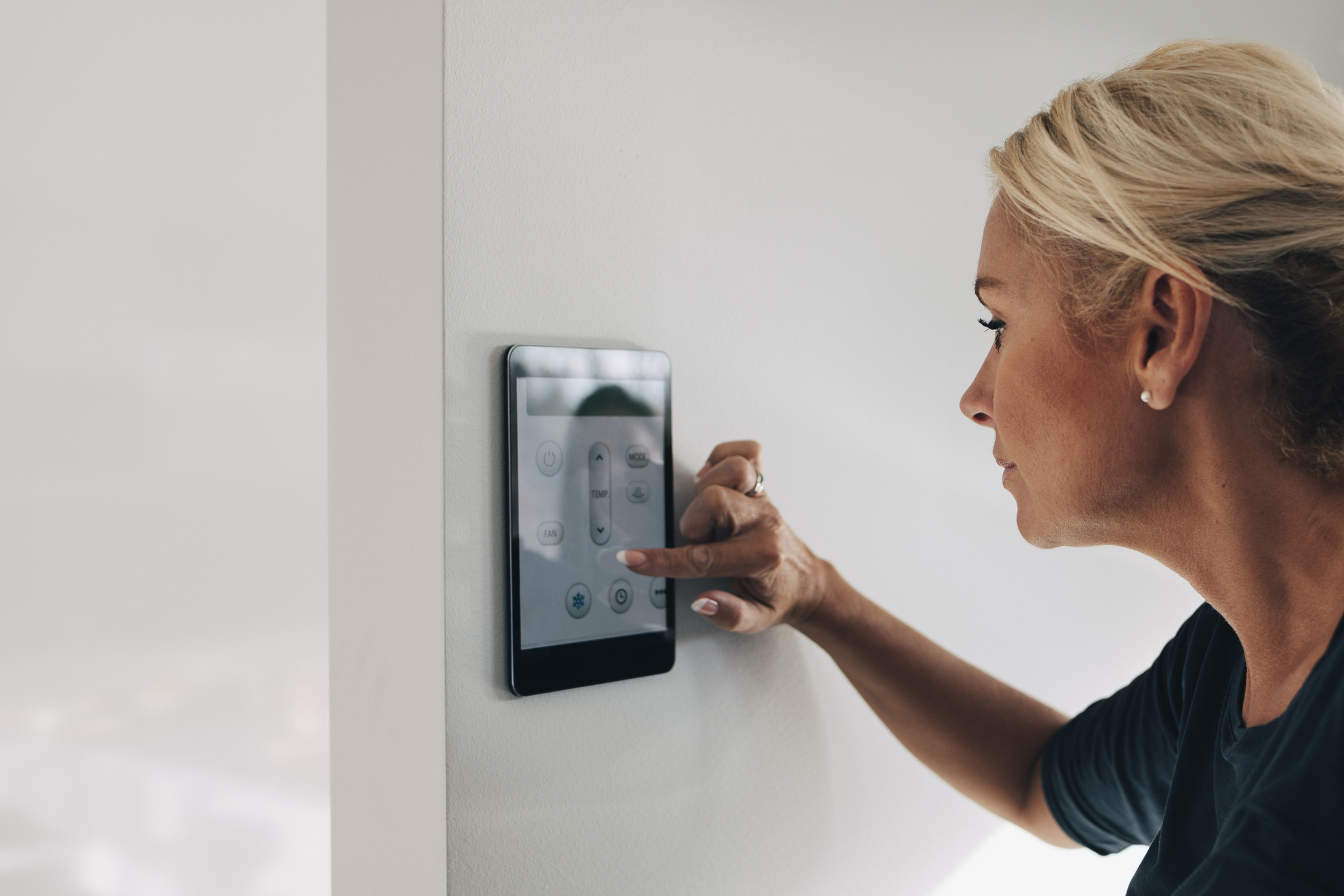 woman interacting with digital thermostat