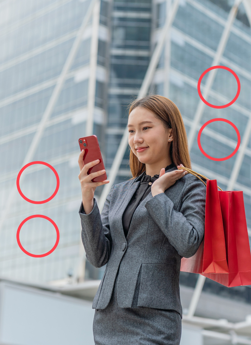 Woman in suit holding shopping bags and looking at phone in hand