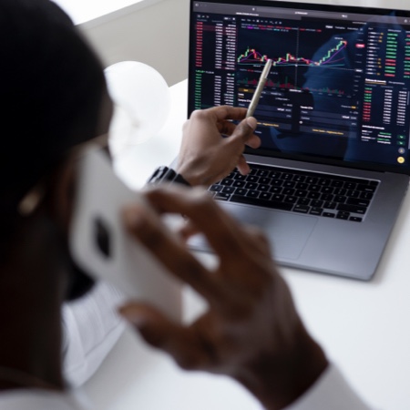 A man viewing financial data on a laptop while talking on the phone