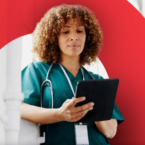 woman in medical scrubs wearing stethoscope holding a tablet