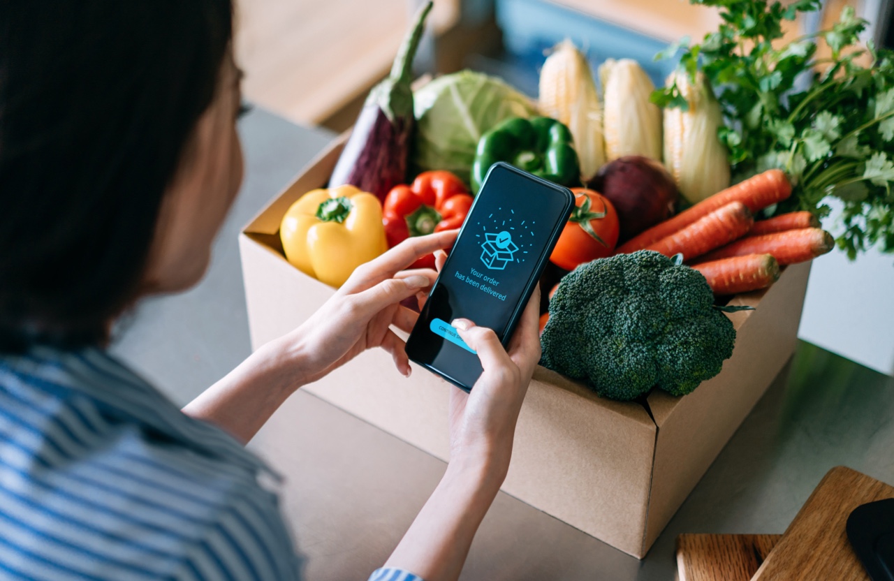 hand holding smart phone screen over an open box of freshly delivered produce