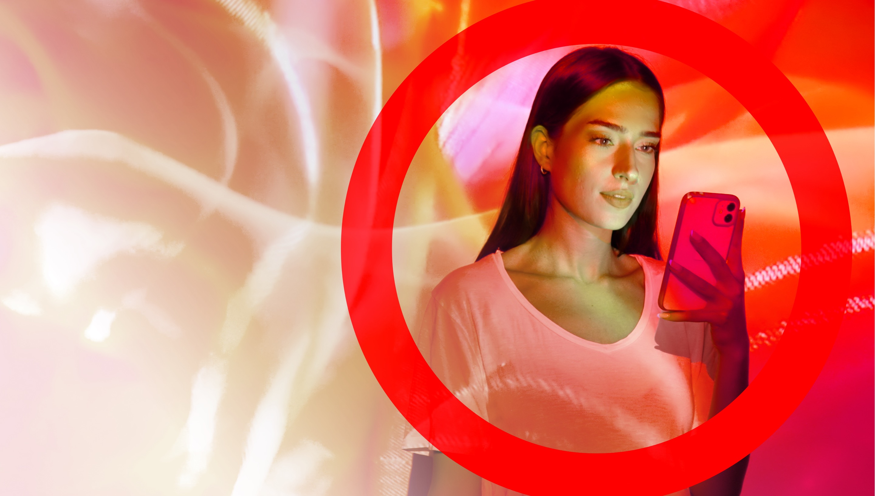 Woman checking her phone against a background of blurry shades of red and peach