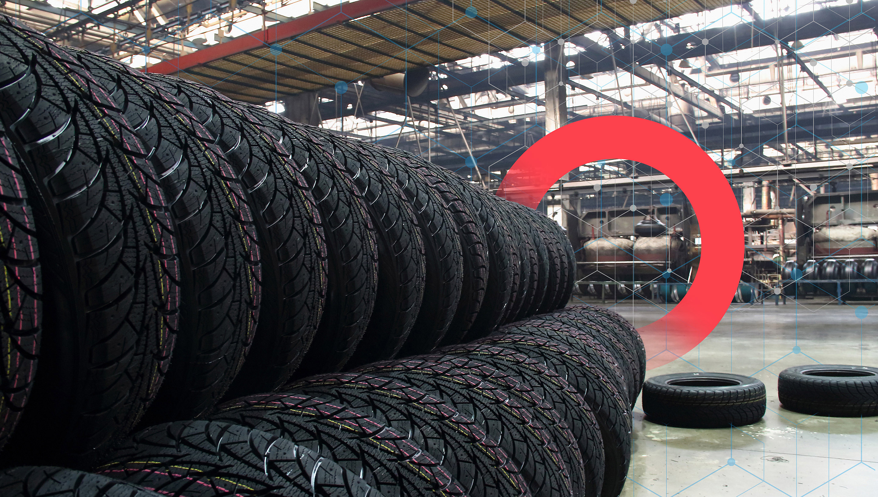 Two stacked rows of new tires line a tire manufacturing plant floor.