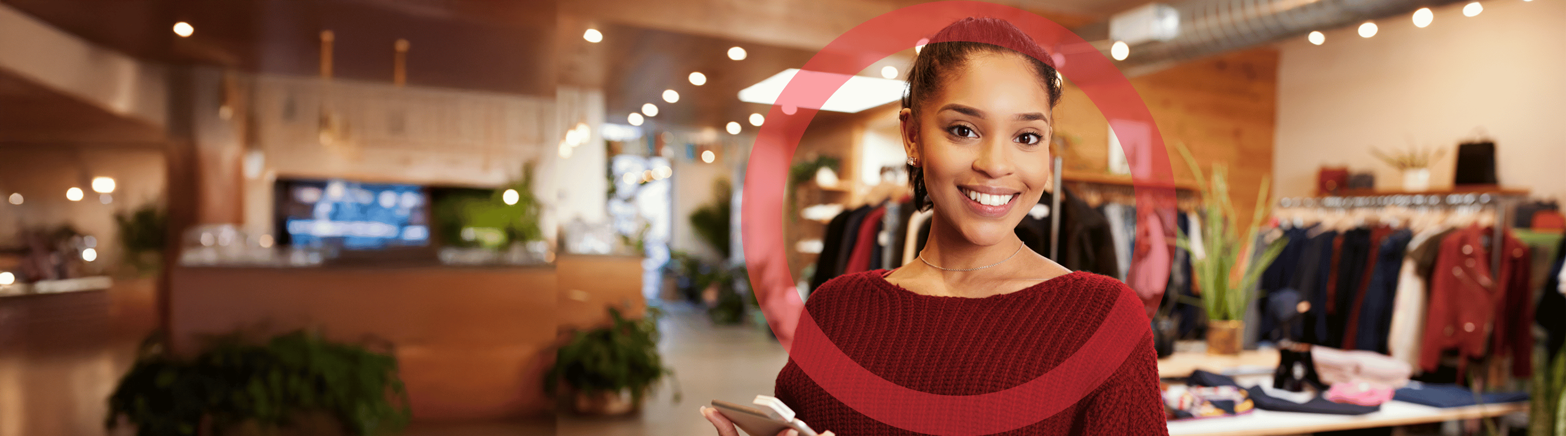 A smiling female retail associate holds a smart tablet in a fashionable clothing store