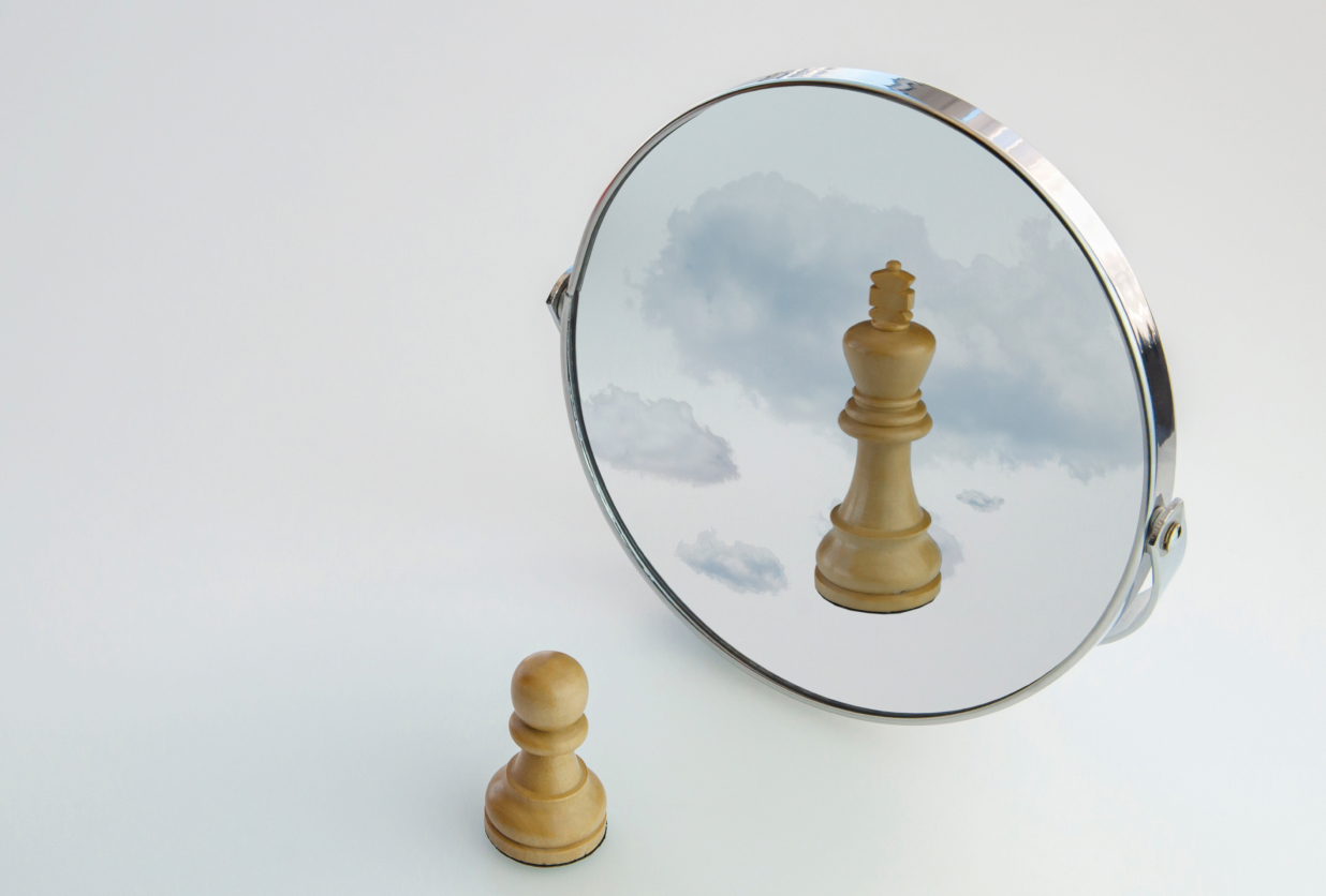 Chess piece reflected in mirror with clouds in background.