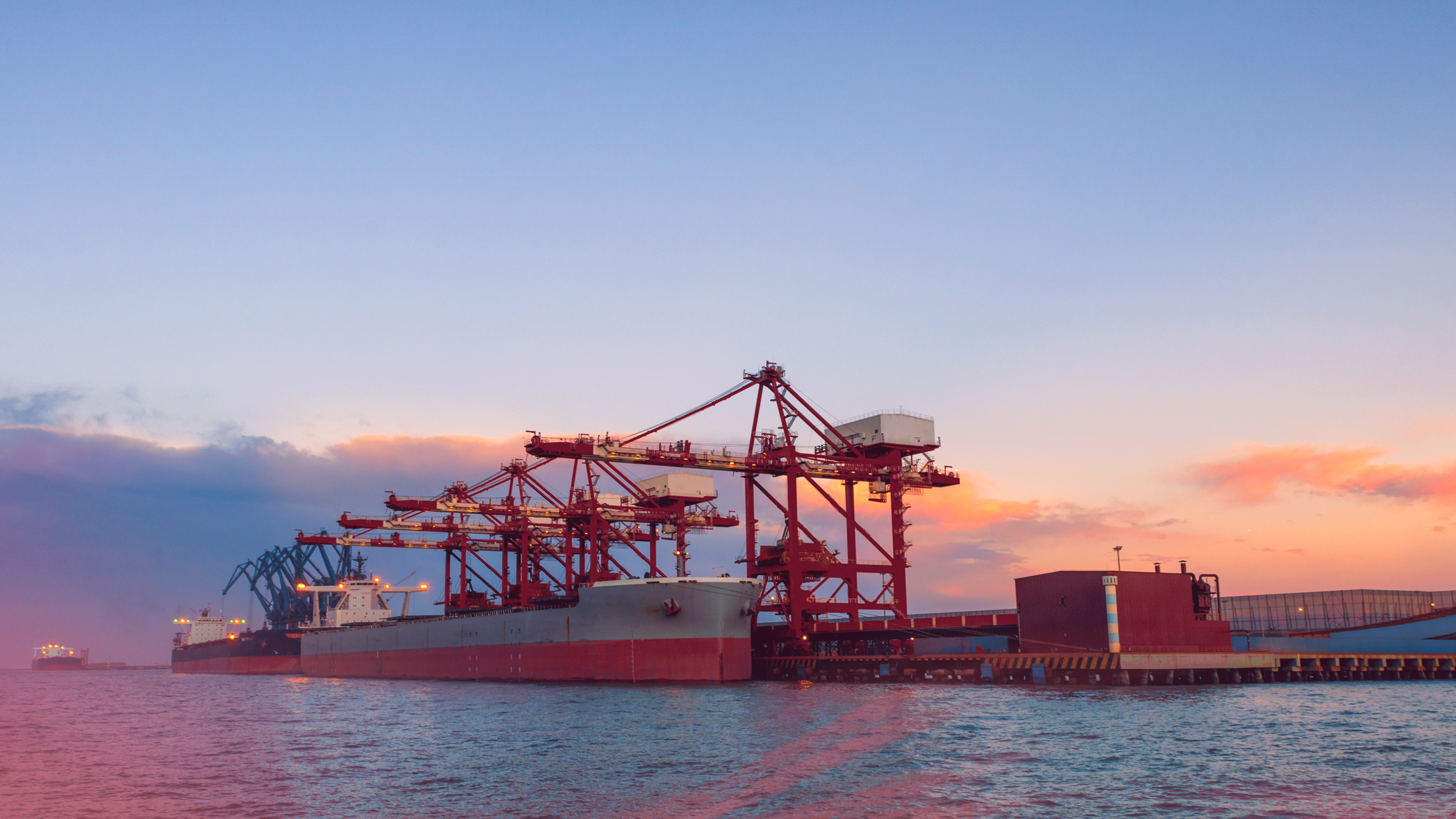 A cargo ship in the water at sunset.