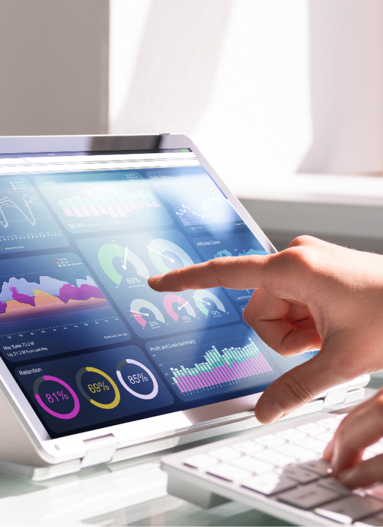 Person interacting with touchscreen laptop displaying colorful data dashboards and charts, while also typing on the keyboard