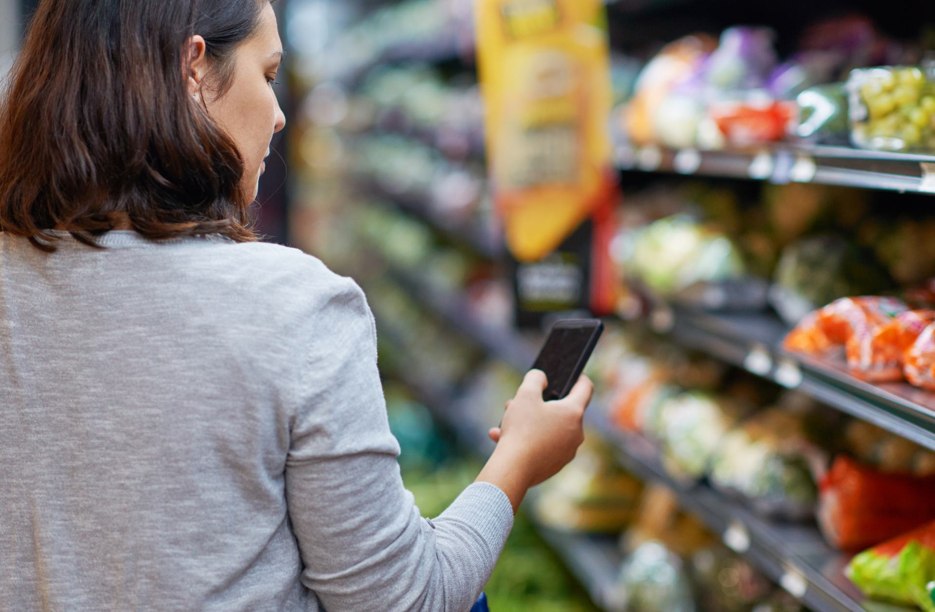 Woman in grocery aisle looking at phone