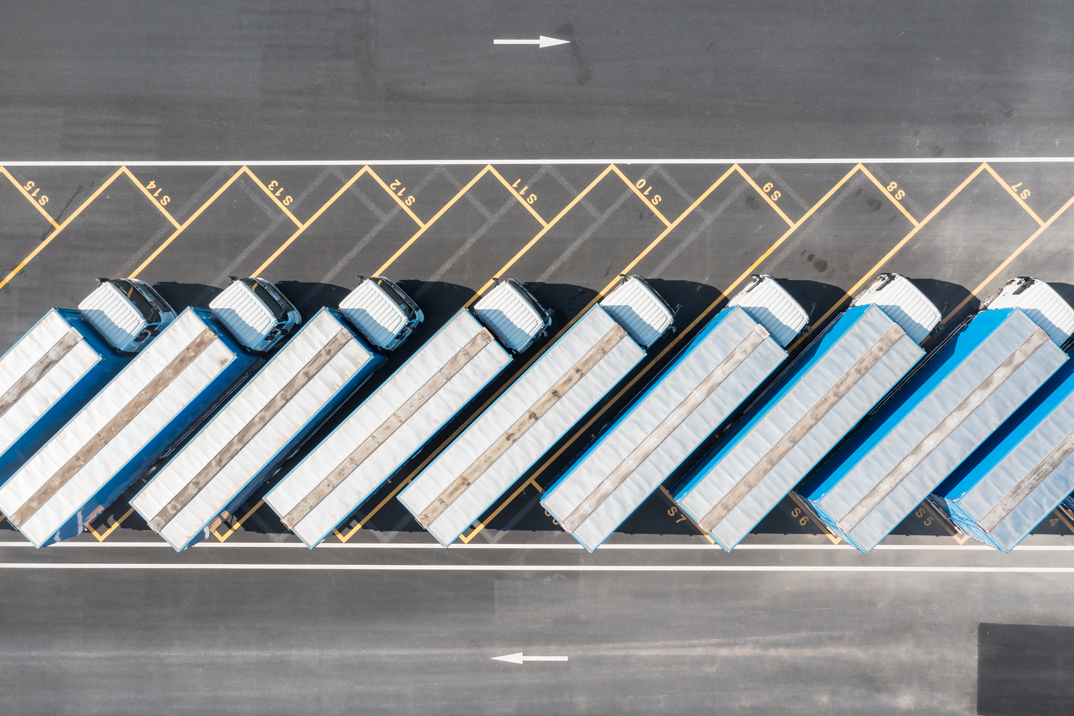 Overhead view of a parking lot filled with several trucks parked in organized rows.