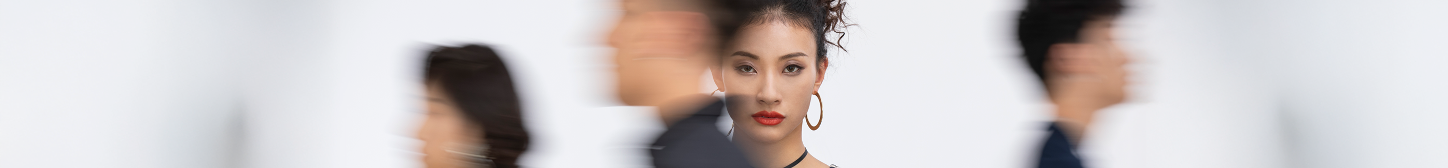 A woman stands with her arms crossed, observing a blur of people walking by.